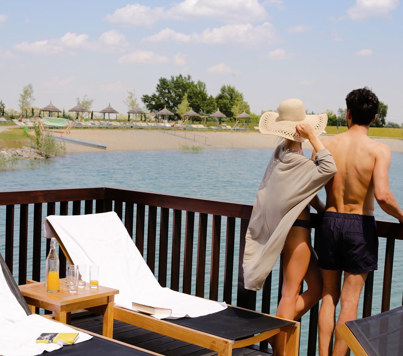 Pärchen steht auf der St. Martins Lodge See Spa Terrasse und genießt den Ausblick auf den Badesee