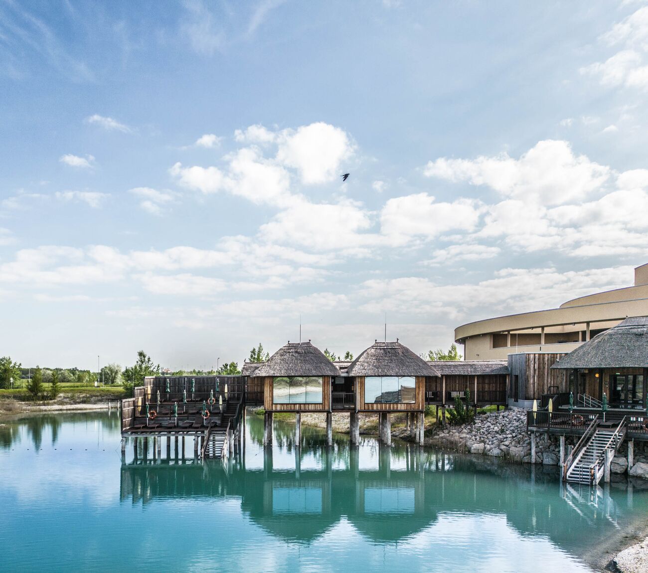Blick auf die See-Sauna der St. Martins Therme von außen über türkisfarbenem Badesee.
