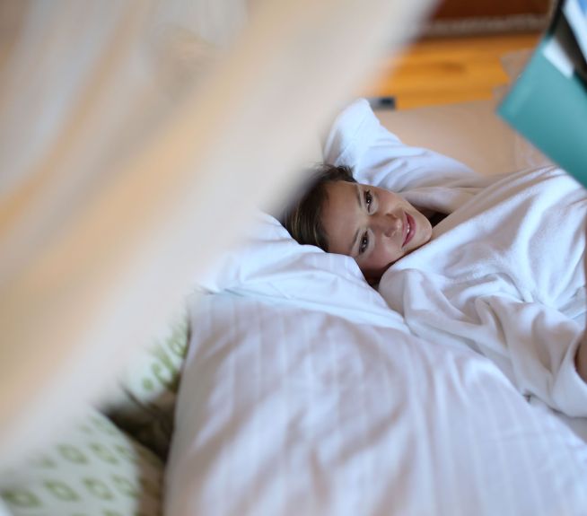 Frau liegt im Bett der Panorama Junior Suite der St. Martins Lodge und liest