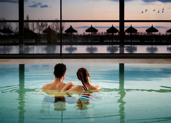 Pärchen genießt den Sonnenuntergang aus dem Innenbecken der St. Martins Therme und Lodge