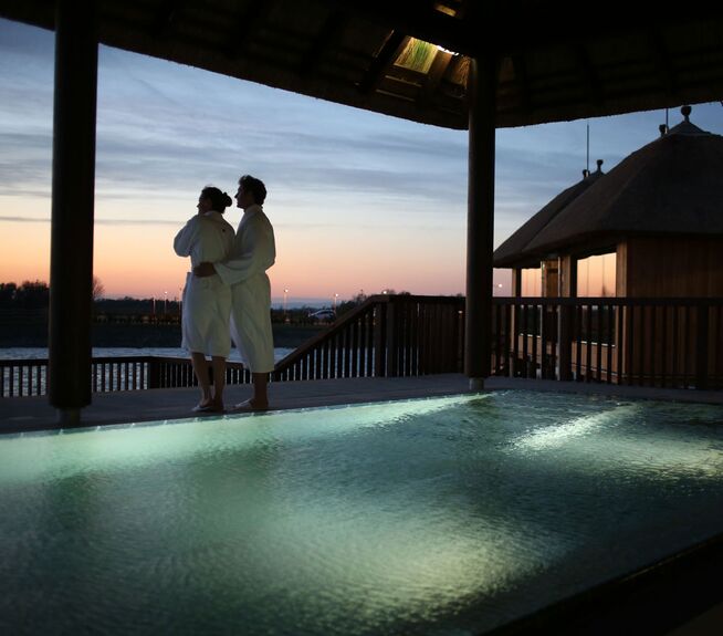 ein Pärchen haltet sich in den Armen und genießt den Sonnenuntergang in der See Sauna der St. Martins Therme