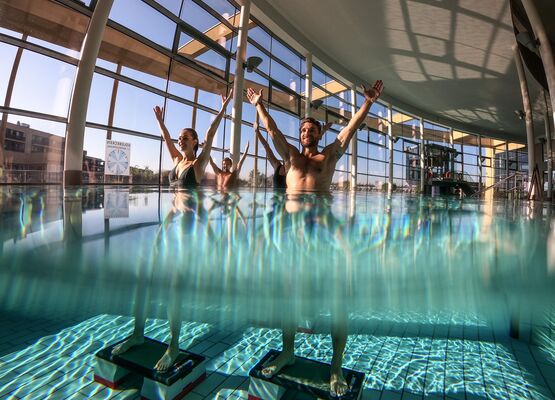 Four people doing water aerobics in the indoor pool at the spa.
