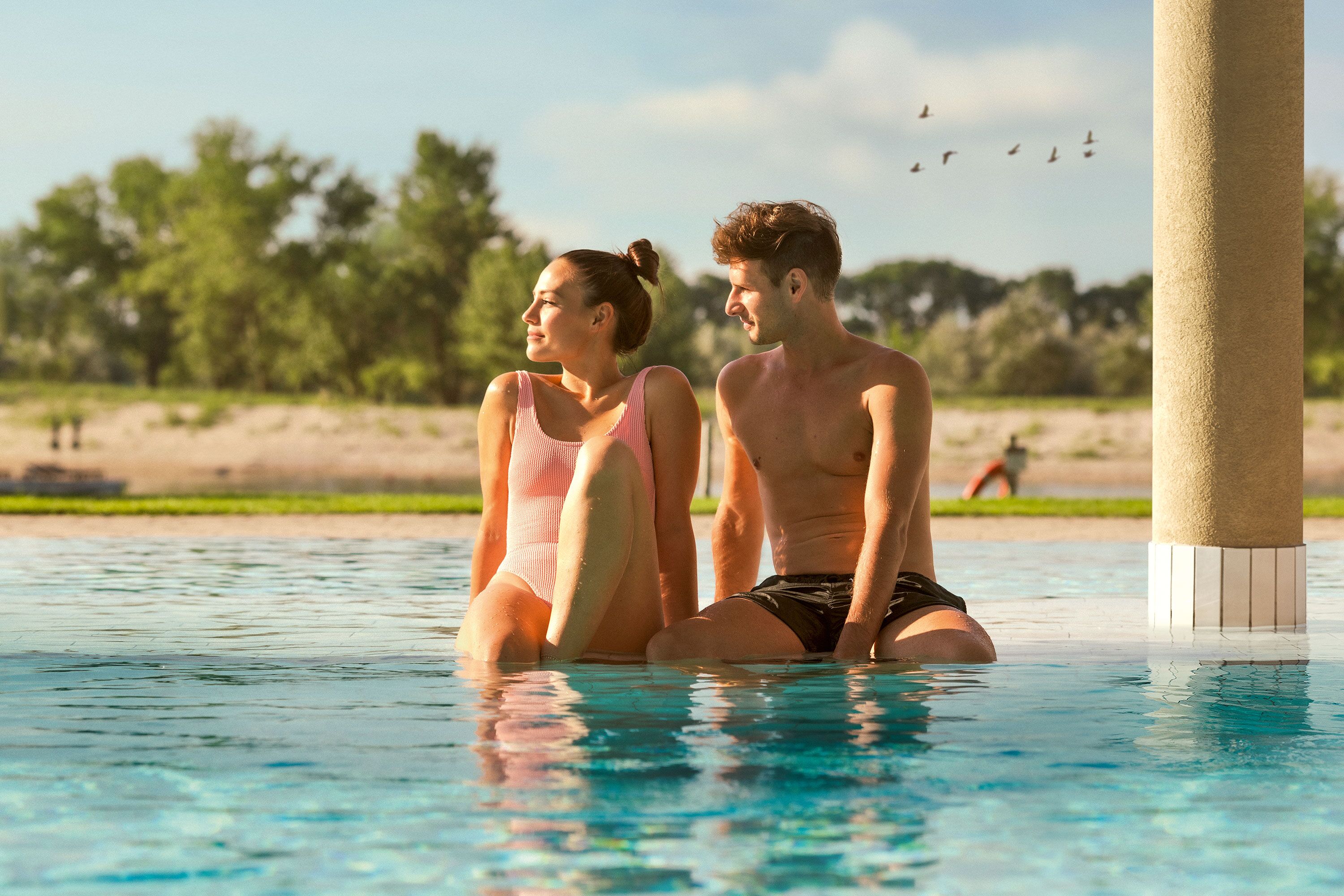 Pärchen genießt die Sonne im Außenpool der St. Martins Therme und Lodge