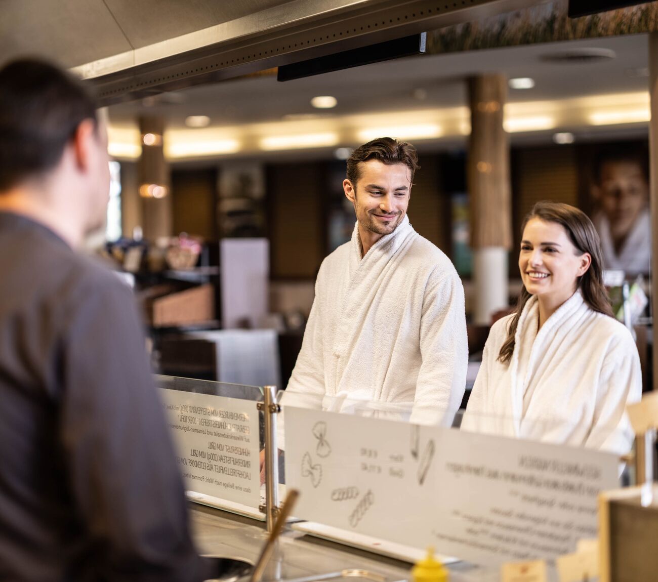 eine Frau und ein Mann bestellen etwas im Marktrestaurant der St. Martins Therme