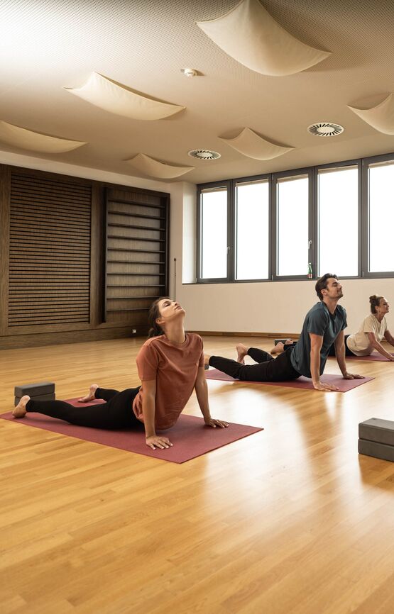 Yogaeinheit mit drei Teilnehmenden und einem Yogameister im St. Martins Fitnessstudio.