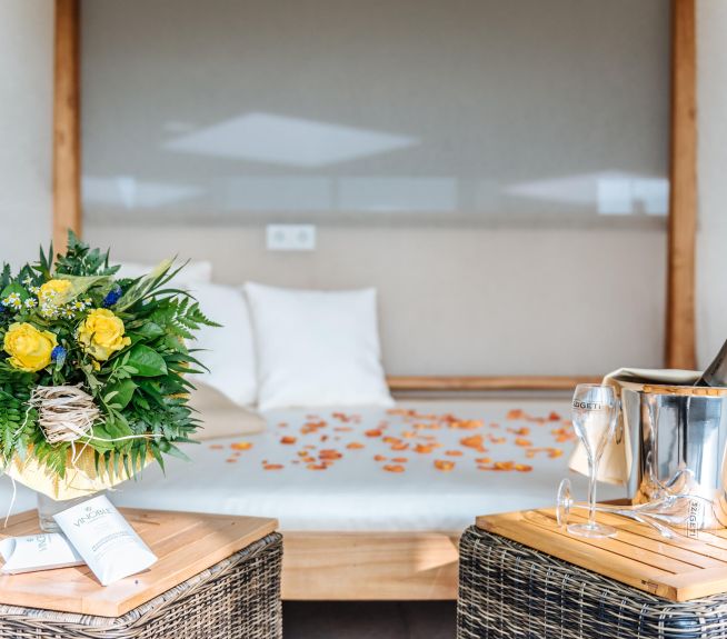 ein Himmelbett im Relax-Tagesurlaub Bereich mit einem Blumenstrauß und Sekt